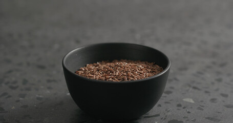 flaxseed in black bowl on terrazzo countertop with copy space
