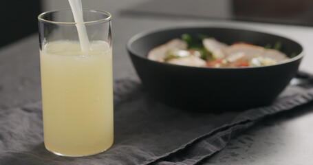 Pour lemonade with salad bowl on background on concrete countertop