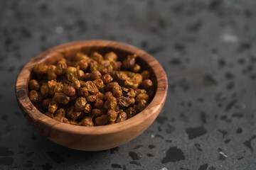 dried seaberry buckthorn in olive bowl on terrazzo countertop with copy space