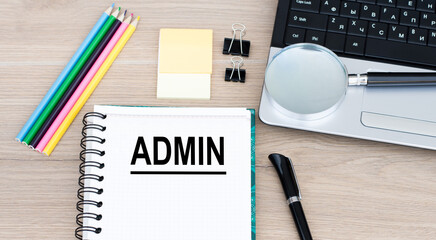 Admin inscription on a notebook, which lies on the table next to a laptop, pen, colored pencils. Business concept