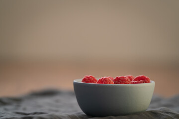 Yogurt with fresh raspberries in blue ceramic bowl on walnut table with copy space