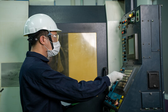 Factory Worker Wearing Protective Mask To Protect Against Covid-19 Are Working And Checking Machine In A Large Industrial Factory.