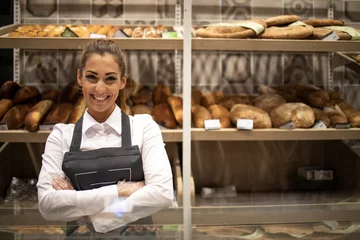 Foto op Plexiglas Portrait of bakery seller with arms crossed standing in front of shelf full of bred bagels and pastry. © littlewolf1989