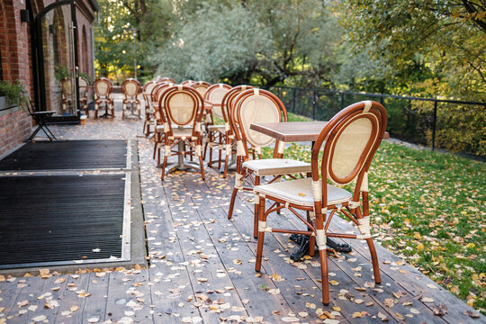 Open restaurant by the river with wooden retro chairs and autumn leafs
