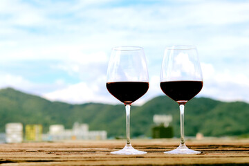Red wine glass  on old wooden floor Mountain view background.