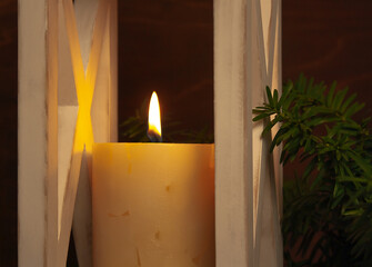 burning candle in a white wooden candlestick