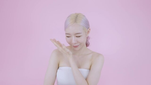 Asian woman finger softy touching face skin by fall in love moment good skin health after cleaning. Modern blonde and pink hair beautiful female model on isolate pink background wear sexy white bra