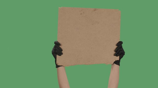 Hands in black gloves pick up a blank poster from a cardboard box. Blank space for your slogan, logo or advertisement. Banner design concept. Isolated a green screen, chroma key. Close up. Slow motion