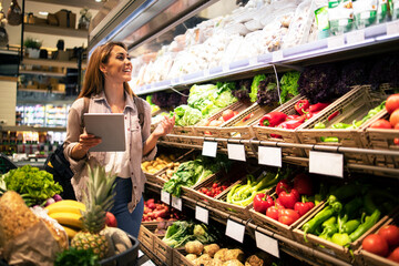 Woman with tablet buying healthy food in supermarket grocery store.
