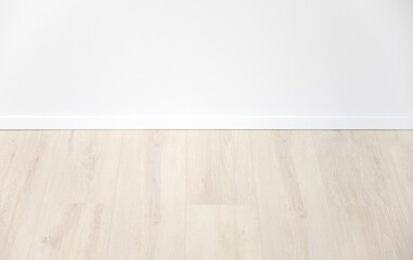 light oak laminate with white baseboard and white wall as background for design concepts