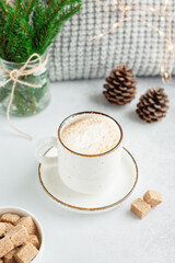 Cup of coffee, scarf and bouquet of fir tree branches. Cozy autumn or winter composition. Scandinavian style