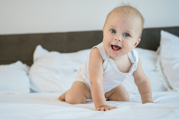 Little baby child lies and rejoices on the bed in the bedroom