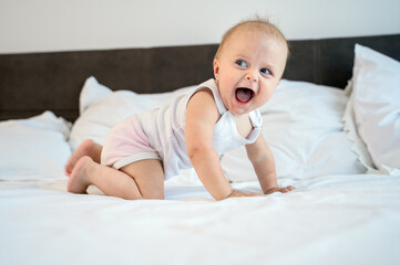 Little baby child lies and rejoices on the bed in the bedroom