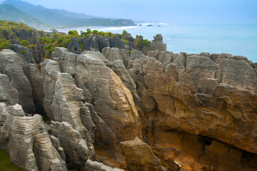 Amazing layer stone formations of Punakaiki Pancake Rocks on gloomy day with dramatic sky, Paparoa National Park, New Zealand