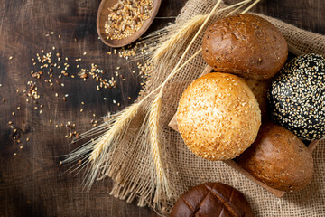 Sesame buns for burgers. Buns in a wooden box on a brown wooden table. Homemade buns with sesame...
