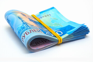 Rolled up bundle of Russian 2000 two thousand rubles banknotes. Lies on a white paper surface. The bills are tightened with an elastic band. Bank loans, deposits and interest