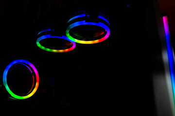 Colorful RGB lights on spinning coolers on gaming computer ,dark background.