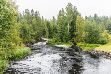 Fototapeta na wymiar Park with the cascades of Akparhvenkoski waterfalls on the Tokhmayoki River, a popular tourist attraction situated near the settlement Ruskeala in Karelia, Russia