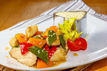 Slices of chicken breast are fried with vegetables: peppers, tomatoes, pea pods.