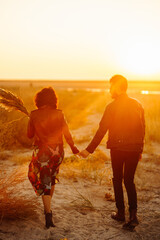 Romantic couple enjoying beautiful sunset walk on the beach travel autumn vacation. Enjoying time...