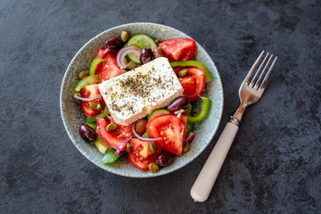 Traditional Greek salad with tomatoes, green peppers, cucumbers, Kalamata olives, capers, red onion and Feta cheese