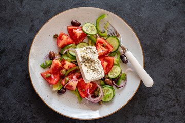 Traditional Greek salad with tomatoes, green peppers, cucumbers, Kalamata olives, capers, red onion and Feta cheese