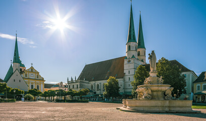Kapellplatz in Altötting bei Sonne,  Stiftskirche. Gnadenkapelle und Brunnen im Gegenlicht