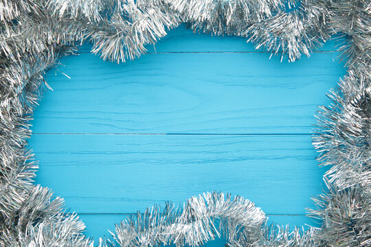 Christmas Silver Tinsel On Blue Wooden Background. This Has Clipping Path.