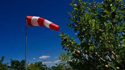 Windsock. Windsock flag. Wind direction indicator. Wind intensity. Windsock in front of blue sky,...