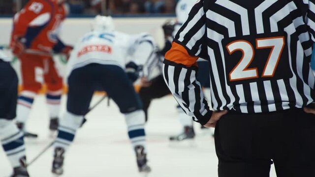Hockey referee holding a puck in face off position. Front view.