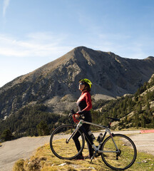 Fototapeta premium Woman road cyclist with her bike observing the mountain in the pyrenees