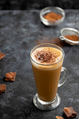 Hot chocolate drink. Tall glass up of fresh coffee latte with whipped cream, isolated on dark background