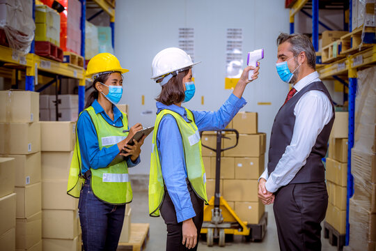 worker used a medical Digital  temperature Thermometer to check staff body temperature before start work in factory ,they wearing face mask the concept of a corona virus [Covid-19] screening. - Powered by Adobe