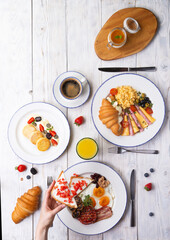 Breakfast is served on a light board. Fried eggs, omelet, croissant, coffee, dessert, place for text.