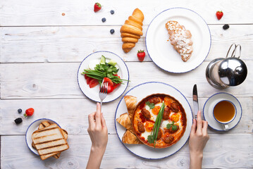 Breakfast is served on a light board. Fried eggs, omelet, croissant, coffee, dessert, place for text.