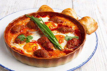 fried eggs with meatballs in a plate on a light board. selective focus