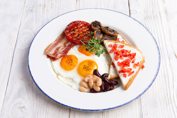 Fried eggs, toast mushrooms and beans in a plate.
