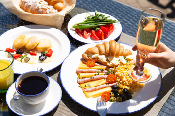 Breakfast outside. Fried eggs, coffee, croissants. Hands in the frame.
