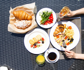 Breakfast outside. Fried eggs, coffee, croissants. Hands in the frame.