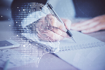 Double exposure of woman's writing hand on background with brain hud. Concept of learning.