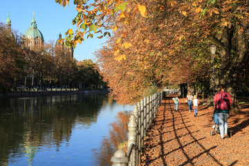 Spaziergang entlang der Isar im Herbst in München mit Blick auf die Kirche St. Lukas