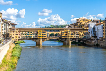 Ponte Vecchio bridge crossing the river Arno, seen from Lungarno degli Acciaciuoli in a bright sunny day, Florence city center, Tuscany, Italy