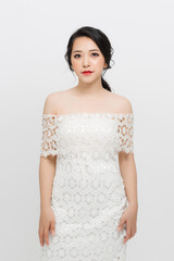 Beautiful young Asian woman with evening make-up wearing a white skinny dress over white background.