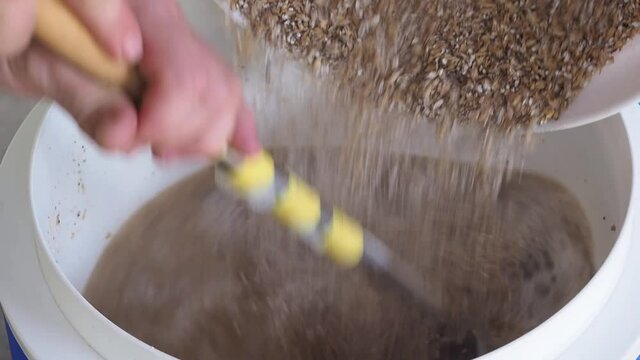 Close-up of stirring malt mash slow motion in a home brewing process. Fermentation of grain for craft beer. Concept of home brew beer making