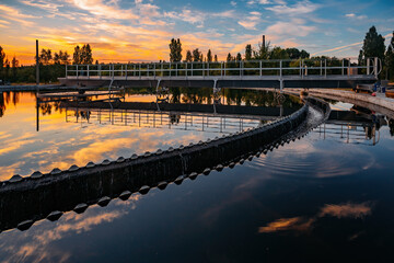 Modern sewage treatment plant. Round wastewater purification tanks at sunset.