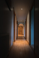 Empty dark corridor in the house with doors, lighting lamps, perspective, in yellow-orange tones, copy space