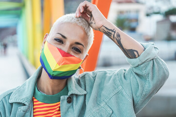 Portrait of gay woman wearing a LGBT rainbow flag mask - Focus on girl's face