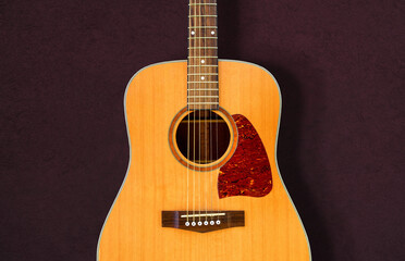 Fototapeta premium Acoustic guitar resting against a dark wall