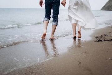 Two pairs of legs of lovers walk on the sand on the seashore.
