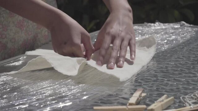 Hands of brunette girl making a spiral pleats in raw textile for tie dye